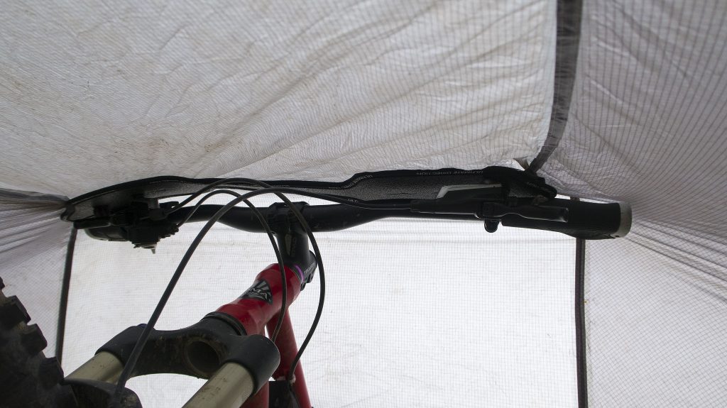 The foam mount attaches to the tarp, and rests on your bike's handlebars